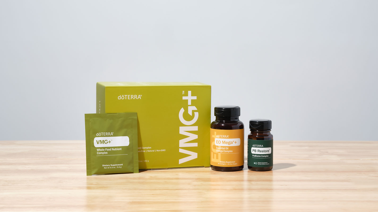 doTERRA VMG+, EO Mega+, and PB Restore sitting on a brown, wooden, countertop surface.
