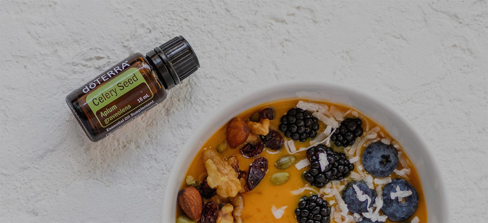 一碗莓果、堅果、燕麥片和一瓶芹菜籽精油。