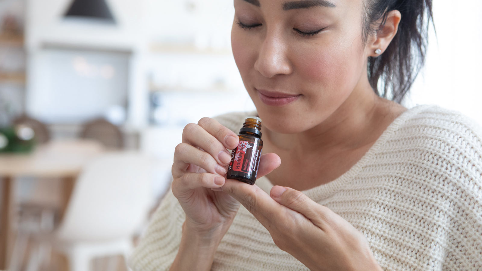 Women lifting Holiday Joy to nose and taking an inhale of the aroma. 