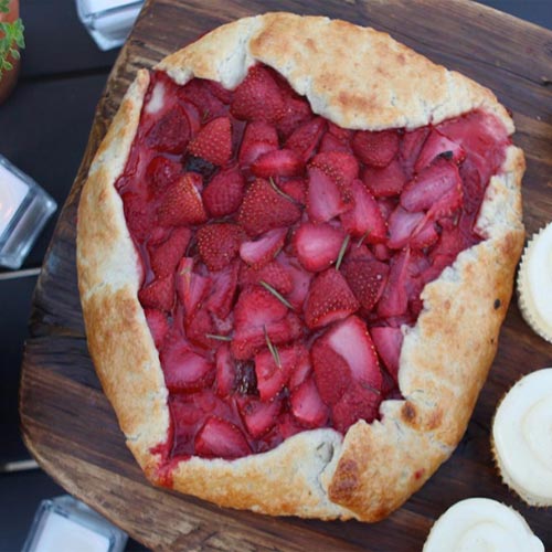 A strawberry tart on a wooden cutting board.