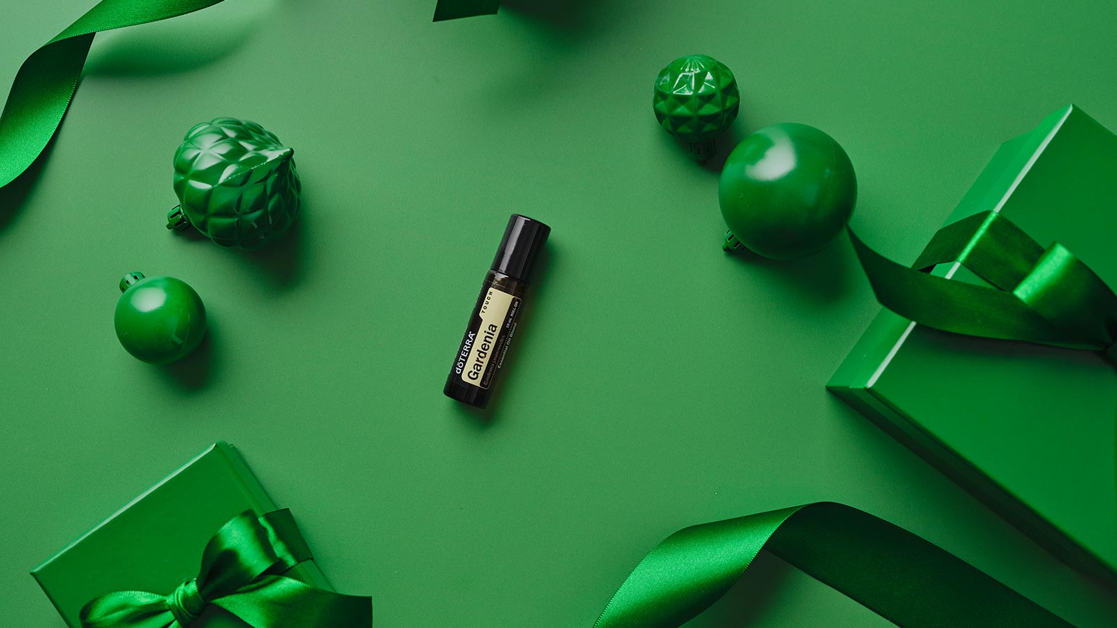 Gardenia Touch laying on a green background, surrounded by similarly colored gifts, ornaments, and ribbon.