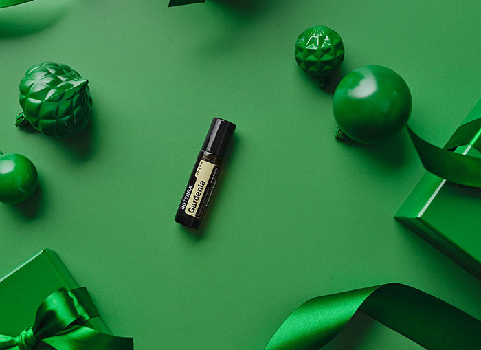 Gardenia Touch laying on a green background, surrounded by similarly colored gifts, ornaments, and ribbon.