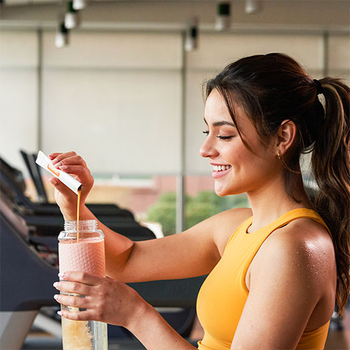 A woman is drinking a MetaPWR Recharge at the gym.