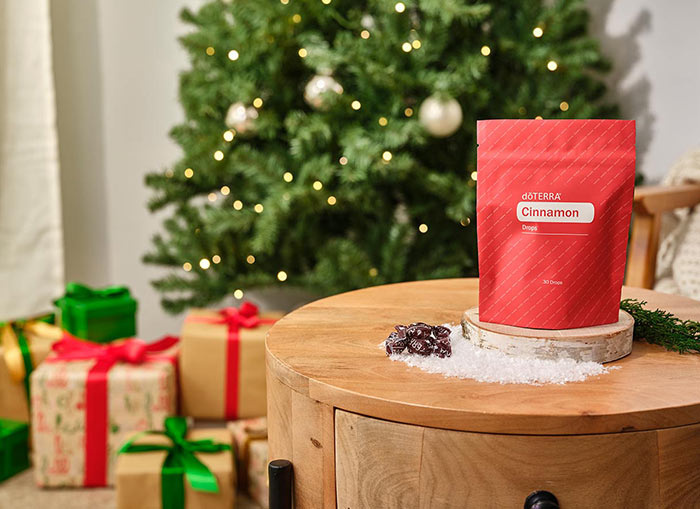 Cinnamon Drops sitting on a round wooden table. A Christmas tree, presents, and a chair with a blanket draped over, in the background. 