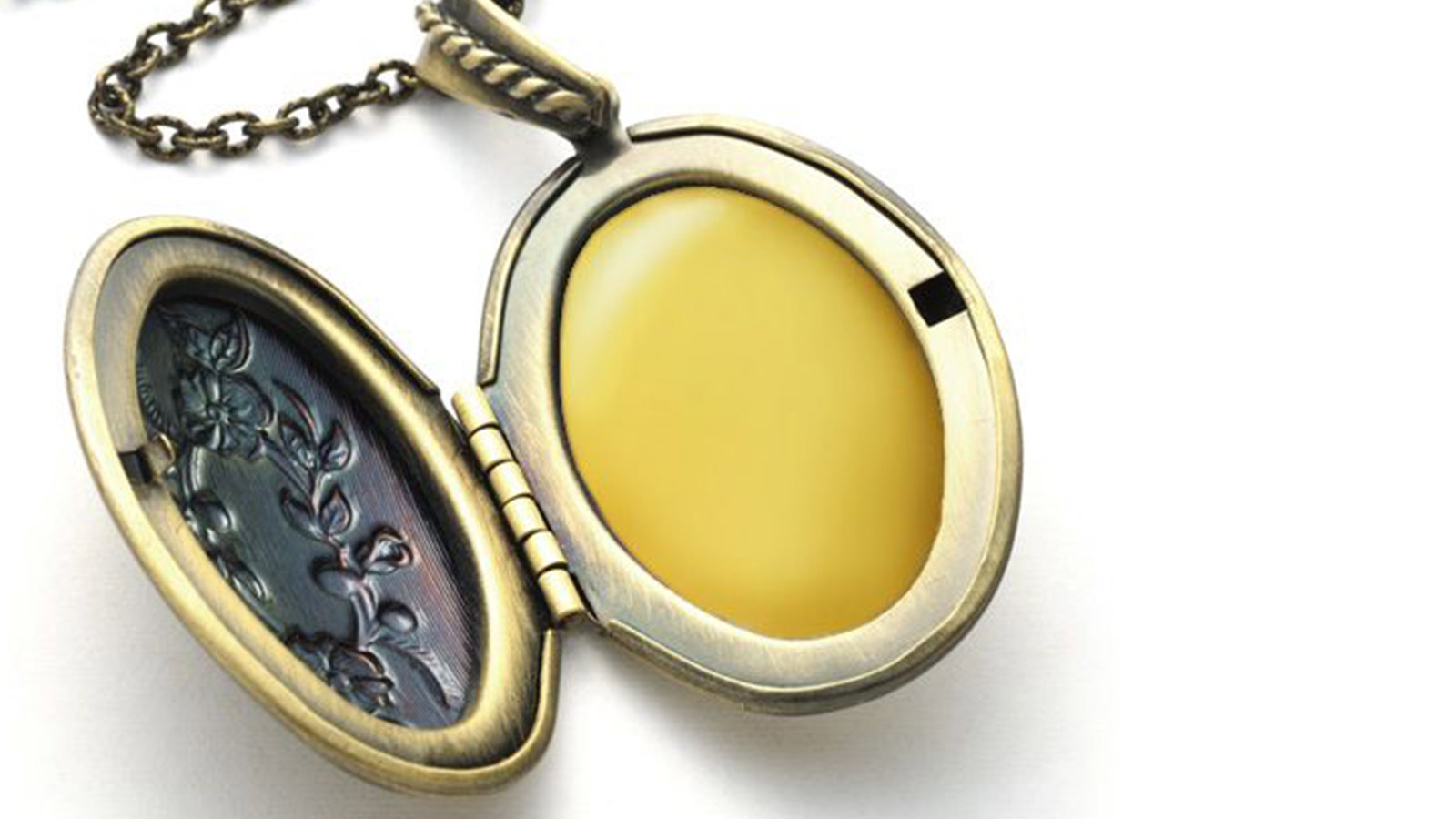 An oval-shaped, golden locket sits open, flowers carved on one side of the chain resting above the locket. 