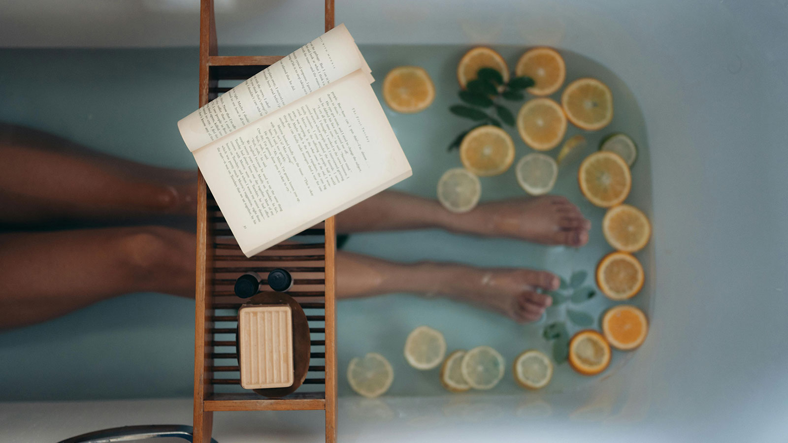A woman reading a book while taking a bath