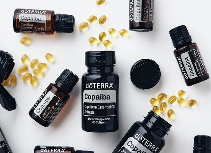 doTERRA Copaiba Softgel bottles and Copaiba essential oil bottles scattered on white surface. 
