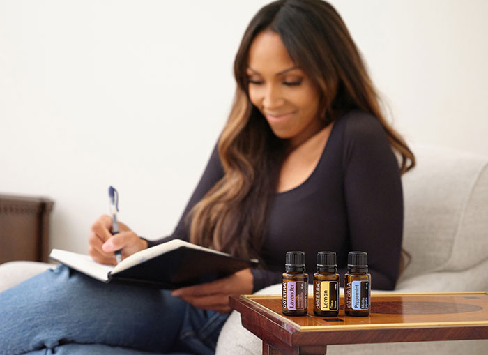 A woman reading a book with peppermint, lavender, and lemon essential oils in the foreground
