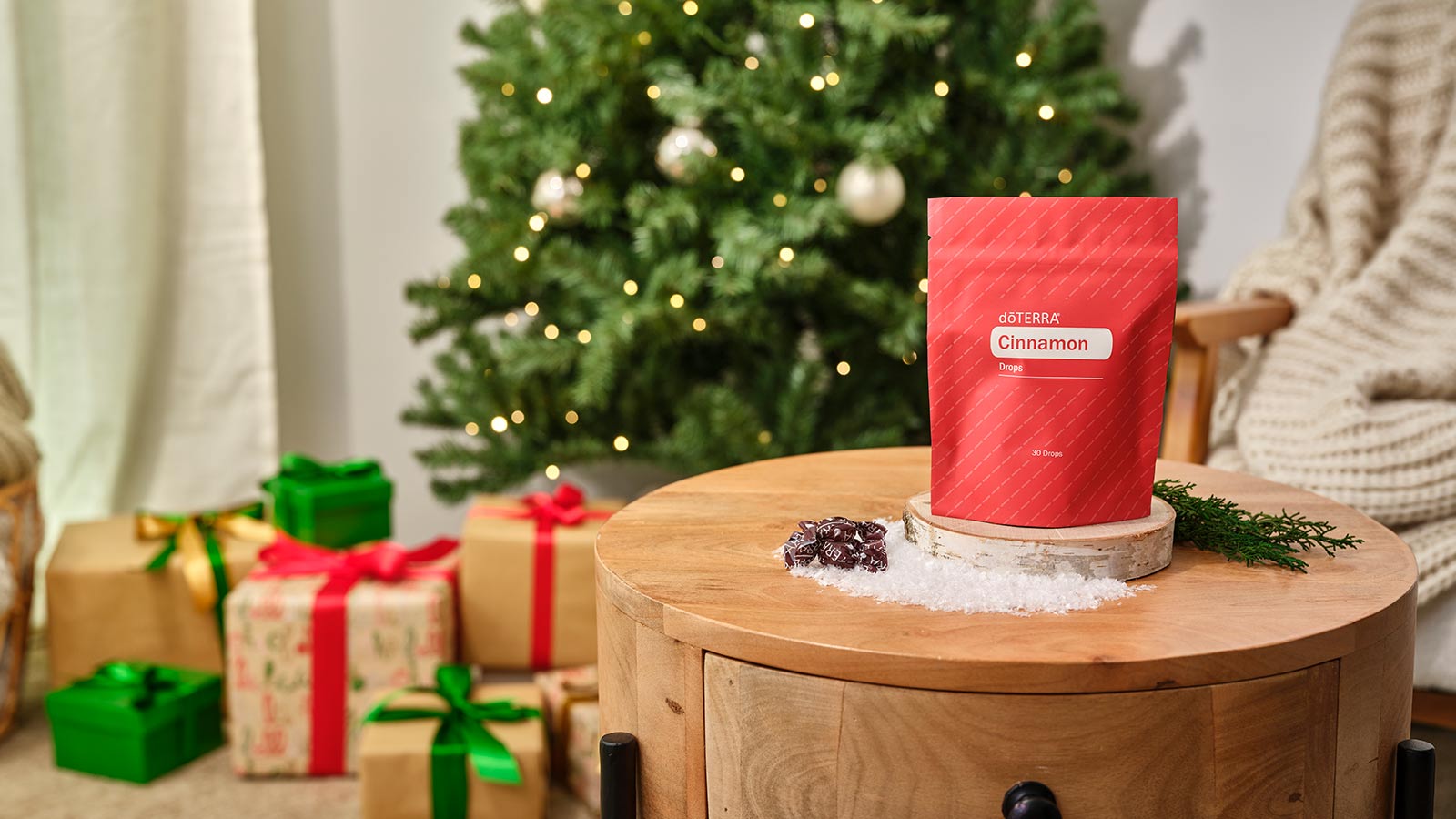 Cinnamon Drops sitting on a round wooden table. A Christmas tree, presents, and a chair with a blanket draped over, in the background. 