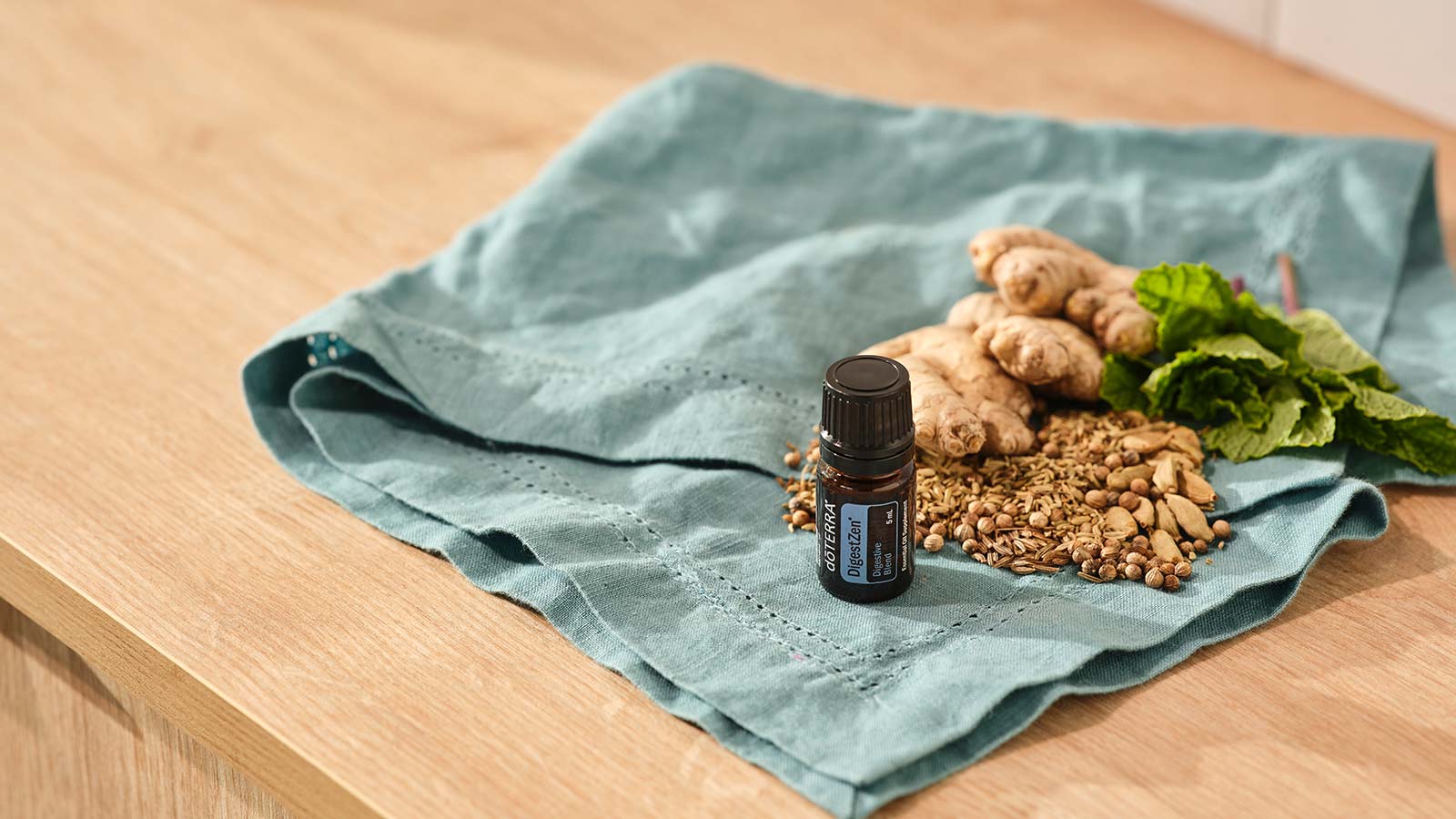 A bottle of doTERRA DigestZen essential oil blend sitting on turquoise cloth on a wooden countertop.  