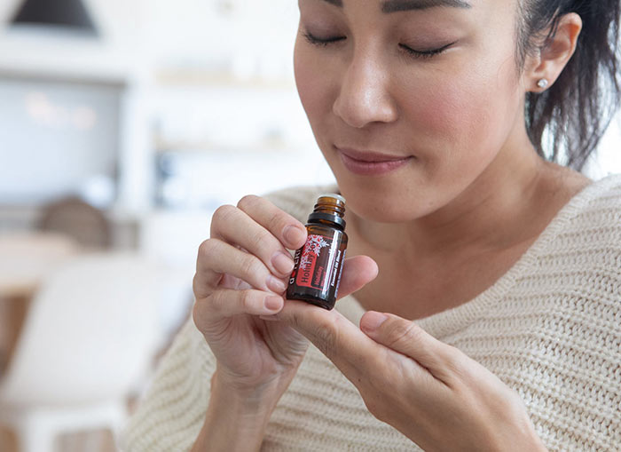 Women lifting Holiday Joy to nose and taking an inhale of the aroma. 