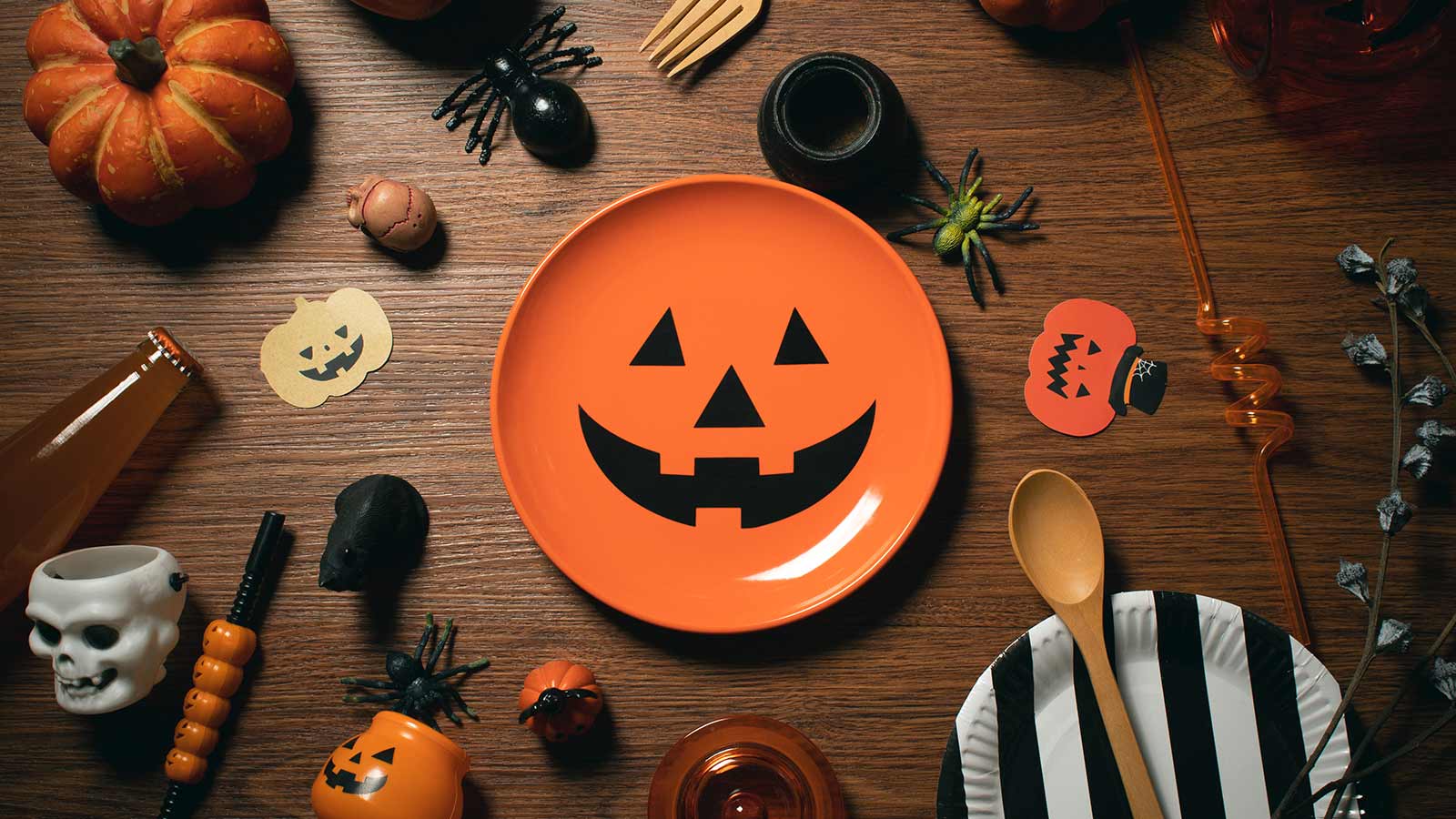 An array of Halloween themed decorations laying on a brown table. 