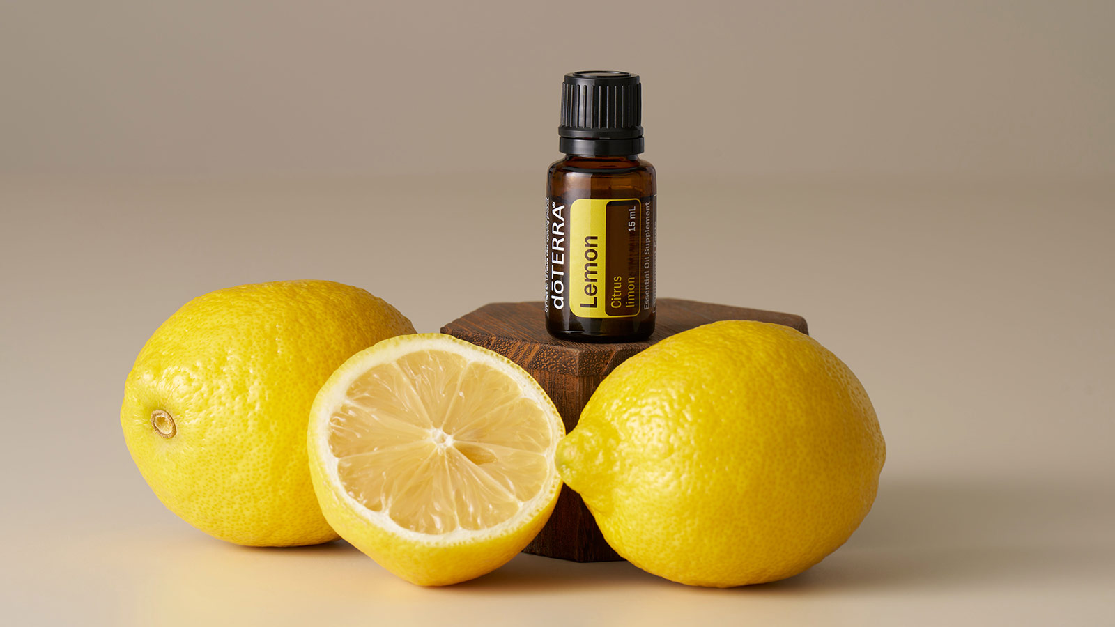 doTERRA Lemon essential oil sitting on raised, wooden surface with lemons surrounding it. 