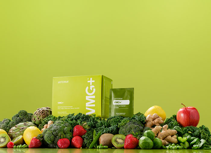 VMG+ box and sachet sitting on a pile of fruits and vegetables, encompassed by a lime-green background.