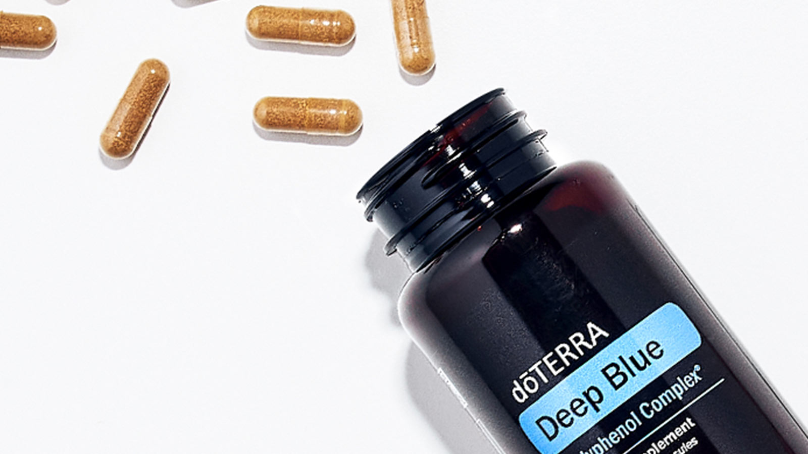 doTERRA Deep Blue Polyphenol Complex bottle lying on a flat surface, with some of the capsules spilling out. 