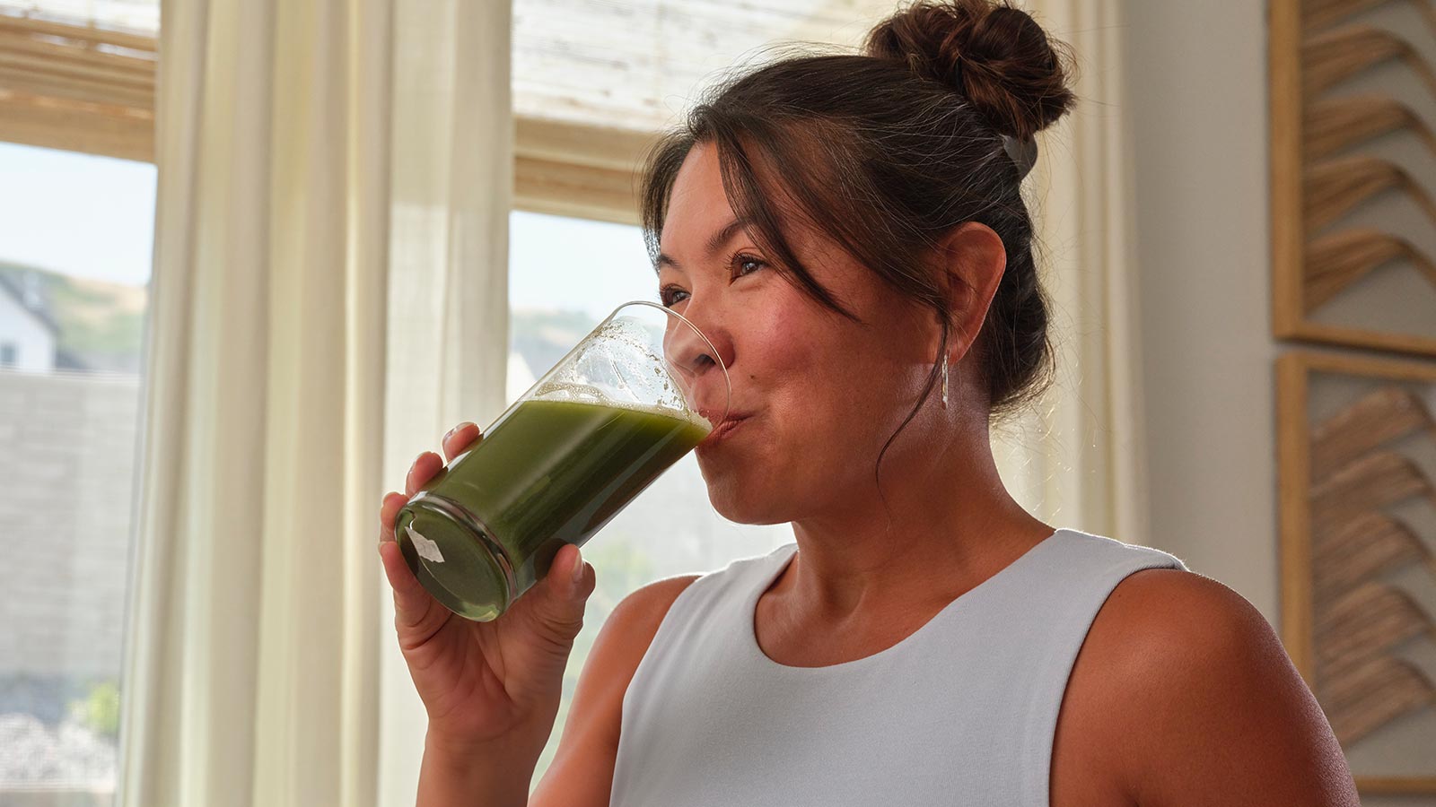 Women sitting on a couch near a window, drinking VMG+ from a glass cup.