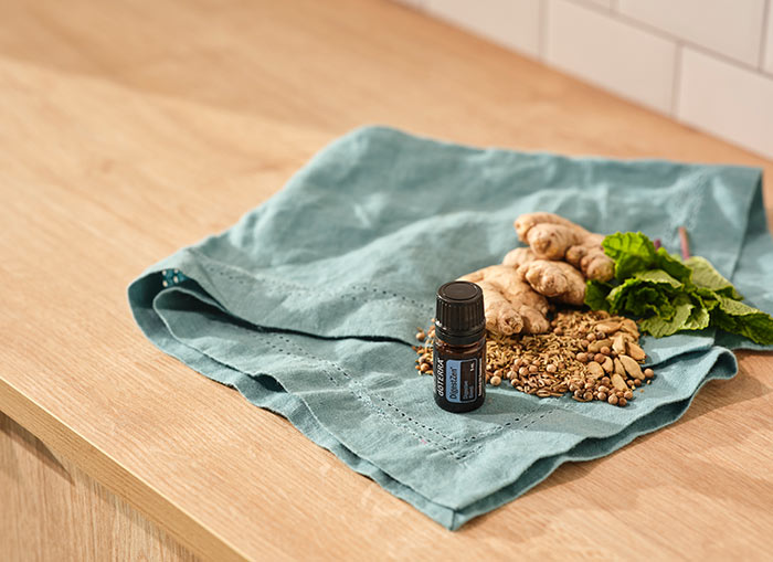 A bottle of doTERRA DigestZen essential oil blend sitting on turquoise cloth on a wooden countertop.  