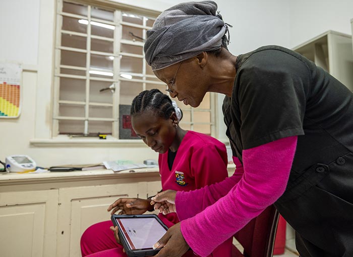 Two women in scrubs looking over an I-pad in a medical office.