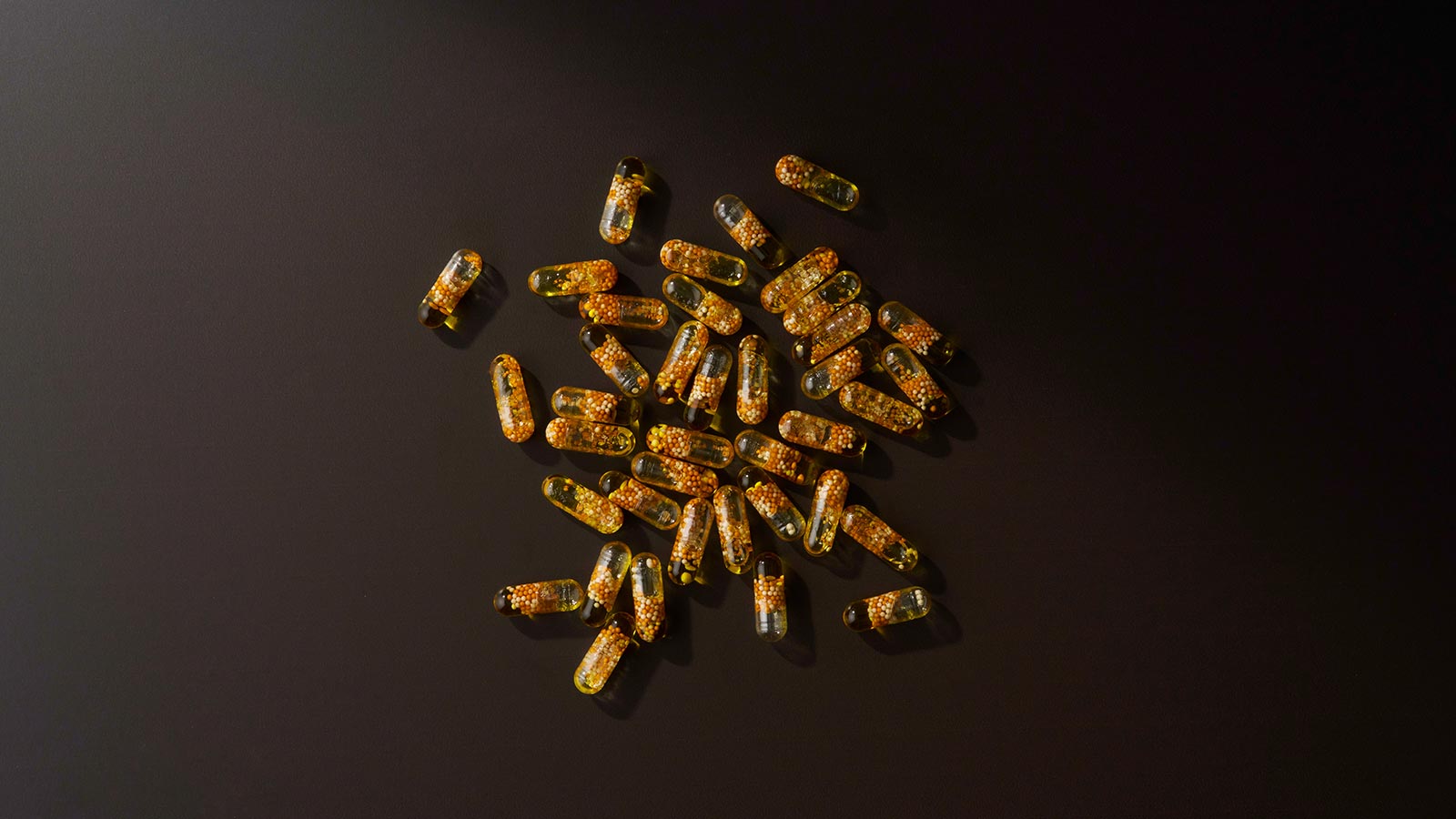 Frankincense Boswellic Acid Complex capsules scattered on a black background. 