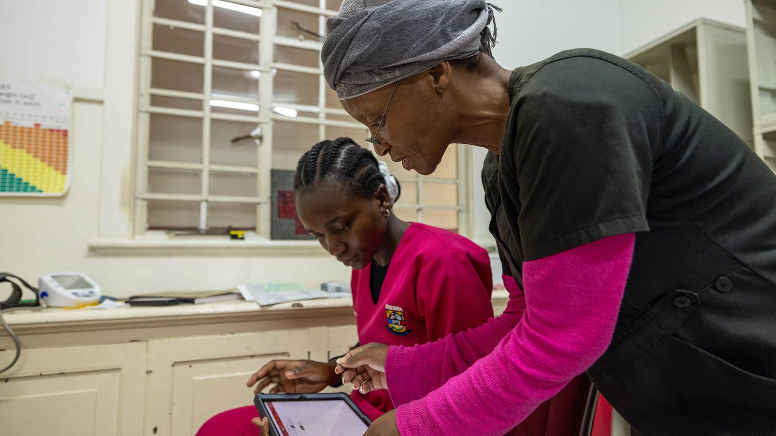 Two women in scrubs looking over an I-pad in a medical office.