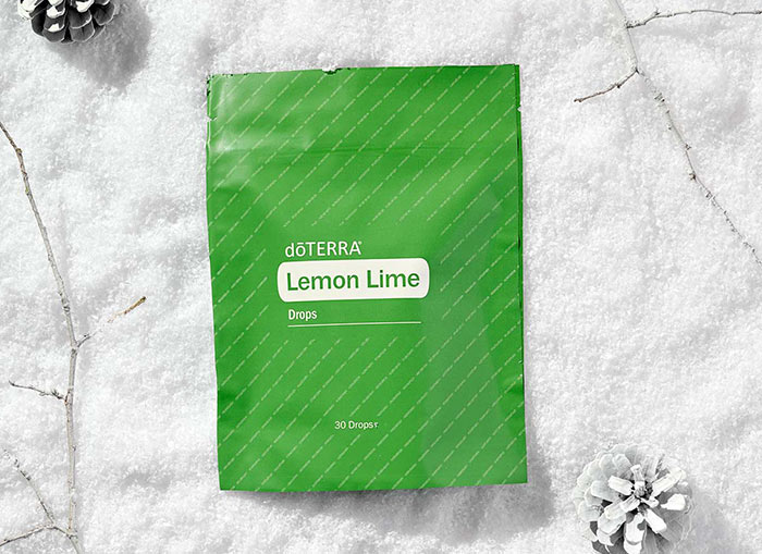 Lemon Lime Drops laying on a soft, snow-like surface surrounded by white twigs and pinecones. 