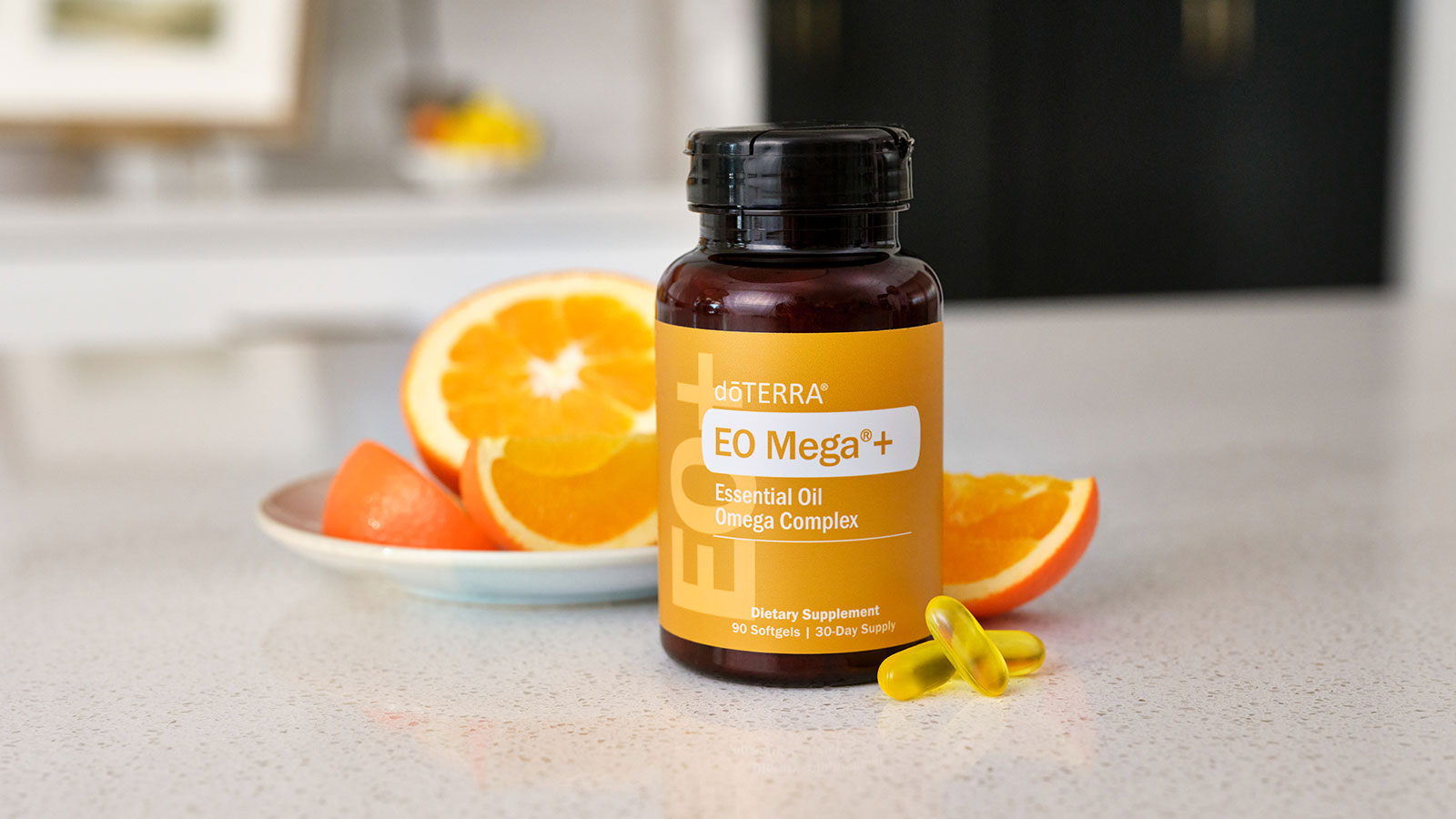 EO Mega+ sitting on white countertop with two pills lying beside the bottle. Orange slices sitting behind the bottle on a small, white plate.