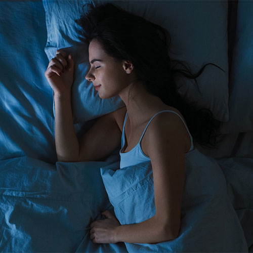 Woman sleeping peacefully in a dark room.