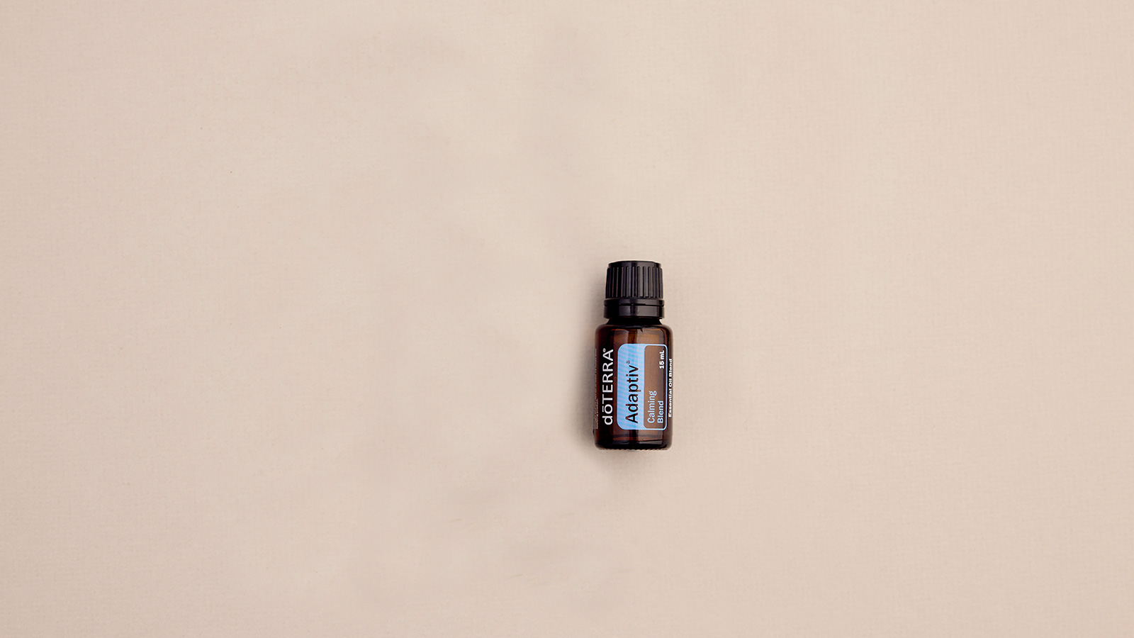 doTERRA Adaptiv essential oil bottle lying flat on plain background.   