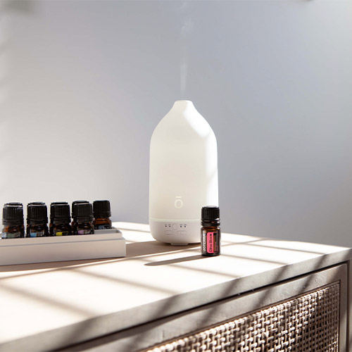 Laluz diffuser sits on a table next to doTERRA essential oils.