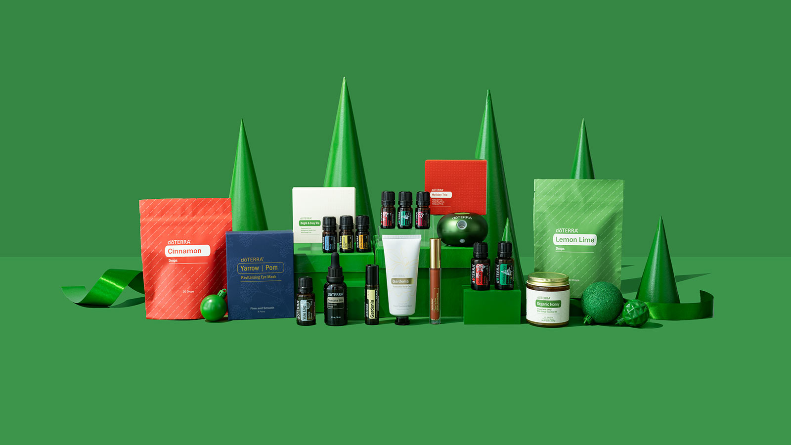 Each product of the doTERRA Holiday Collection, featured with a green background and pointed green trees.