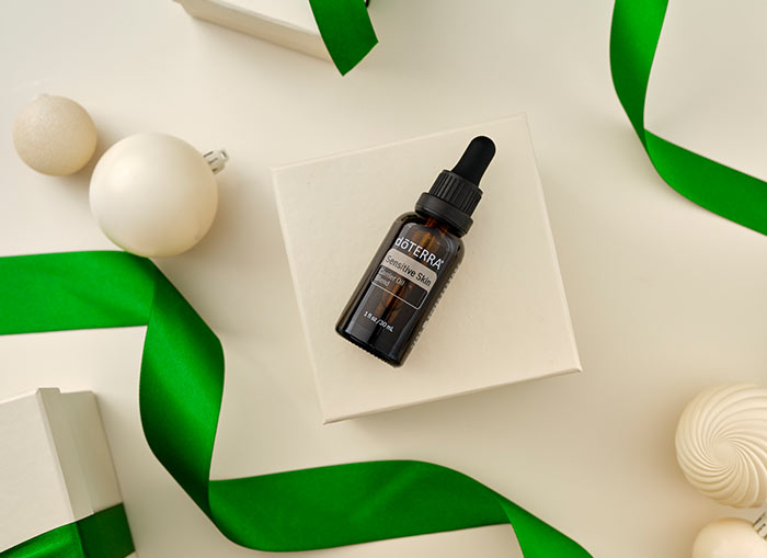 Sensitive Skin Carrier Blend laying on white box, surrounded by white ornaments and green ribbon.