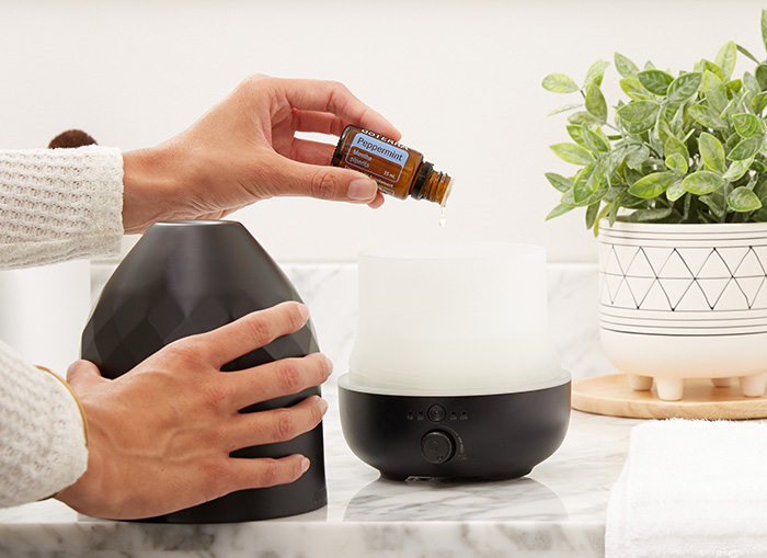 Someone adding peppermint drops to a diffuser